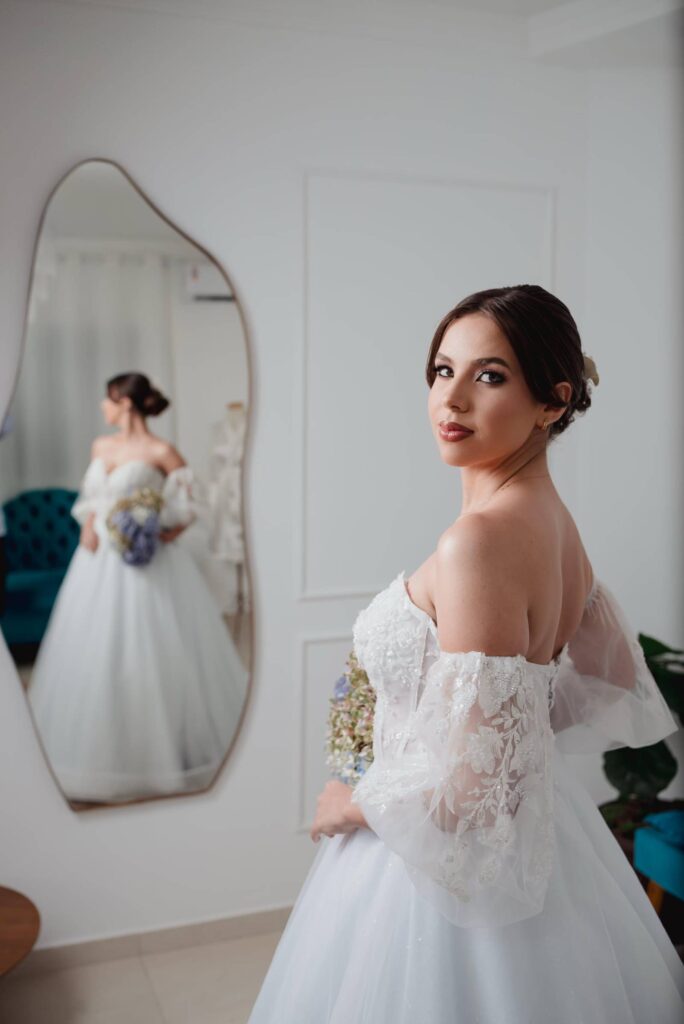 Bela noiva em vestido de casamento com espelho, preparando-se para a cerimônia em ateliê de beleza.