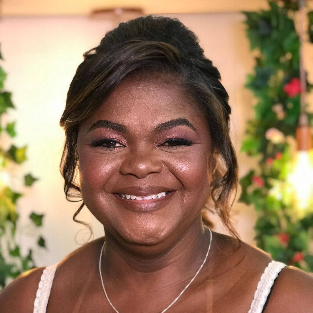Uma bela produção em Governador Valadares, com pele negra e uma linda base iluminada com o tom exato da cor da pele. Sorridente com batom merrom chocolate nude. Delineado na linha d'água levantando o olhar. Aplicação de cílios com aspecto natural. Sombras um pouco mais claras no centro migrando para um vinho muito elegante nas extremidades. Sobrancelhas bem feitas. Contorno e iluminação bem executados. Um lindo penteado com coque semipreso, cabelo escuro liso, com mechas cor de mel. 