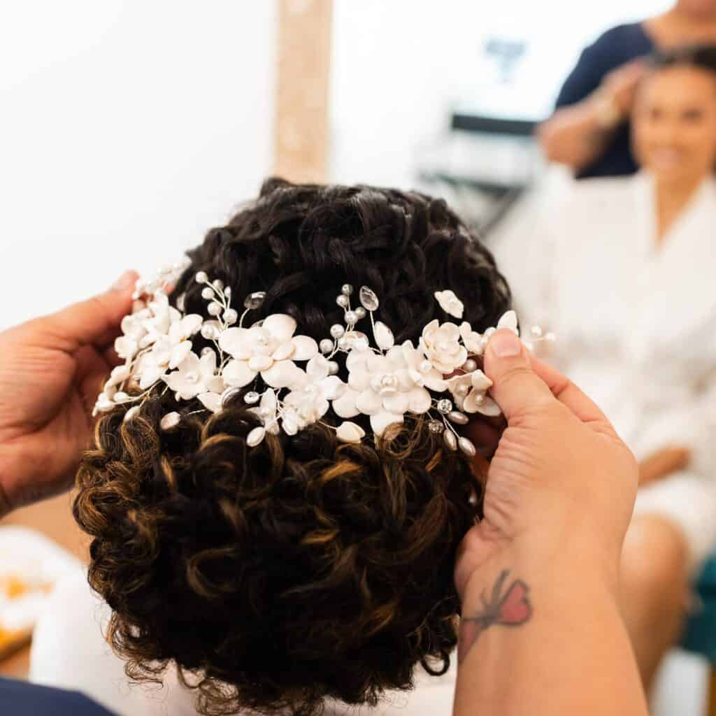 Cabelo cacheado com tiara de flores para cerimônias de casamento ou eventos especiais.