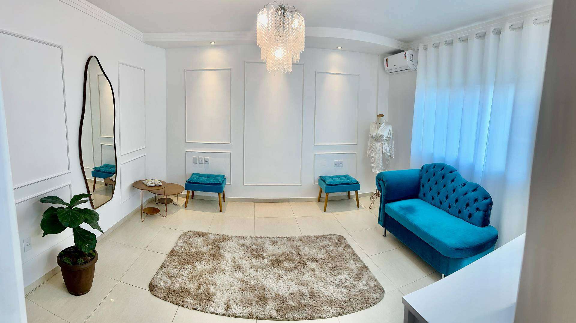 Salão de beleza elegante com decoração moderna, poltronas azuis, espelho decorativo, plantas e iluminação suave, ideal para procedimentos de estética e beleza em Governador Valadares.